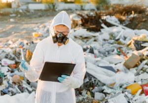 Researcher looking at plastic landfill analyzing environmental policy